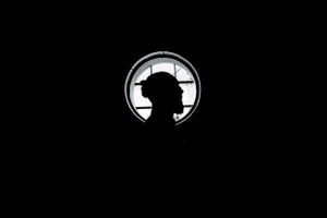 Dramatic silhouette framed in a circular window creating a mysterious backlit portrait.