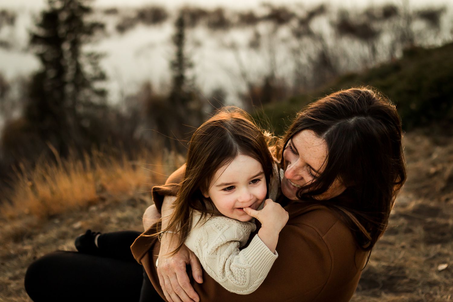 Beautiful mother daughter moment at golden hour during fall family photos in Glenmore Reservoir Calgary AB.