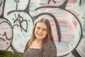 Fun outdoor portrait against colorful graffiti wall with natural lighting.