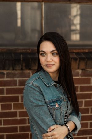 A casual portrait against a brick wall wearing a classic denim jacket.