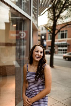 Street style portrait with checkered outfit against commercial building windows.