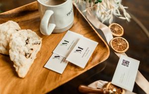 Coffee mug and brand cards arranged on wooden tray with dried citrus slices.