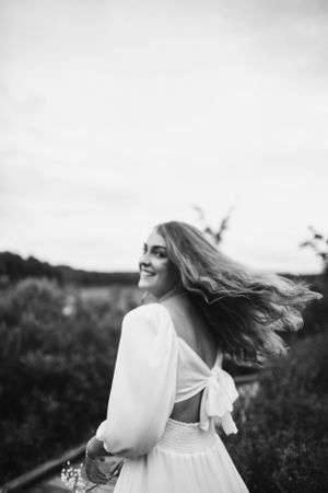 Artistic black and white portrait with flowing dress in natural outdoor setting.