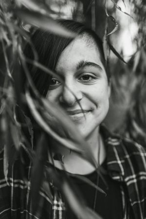 Artistic black and white portrait through foliage with natural shadows.