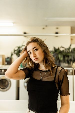 Indoor fashion portrait with sheer black top and warm lighting.
