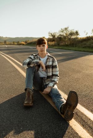 A casual portrait on an empty road wearing plaid flannel and jeans at golden hour.