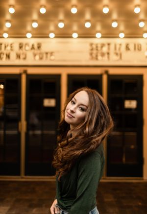 Warm-toned portrait under vintage theater marquee lights.