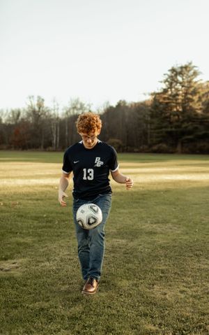 Soccer player practicing ball control on field at golden hour.