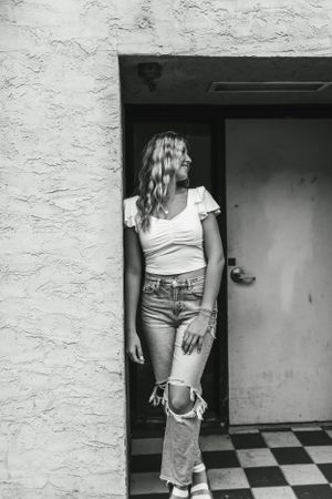 Black and white portrait in a doorway with checkered floor and textured wall.