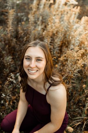 Portrait in burgundy dress against autumn foliage background.