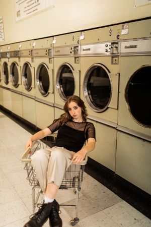Artistic portrait in laundromat with vintage washing machines and metal cart.