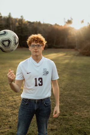 Soccer player in white jersey number 13 with ball during sunset practice.