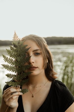 Artistic portrait with fern leaf creating shadow across face at sunset.