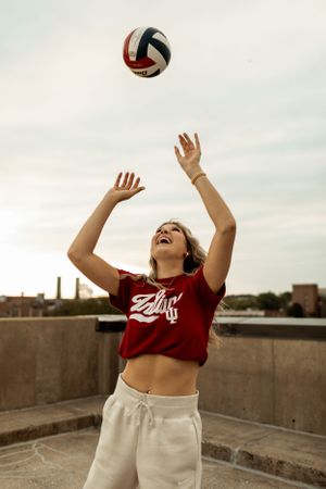 Athletic shot of person playing volleyball on an urban rooftop in casual sportswear.
