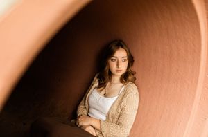 Portrait featuring soft beige and peachy tones in an architectural curved space.