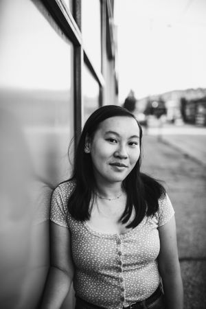 Black and white portrait of musician in patterned top against urban backdrop.