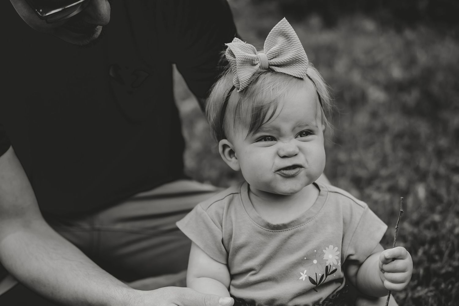 Black and white portrait of a baby wearing a large bow headband.