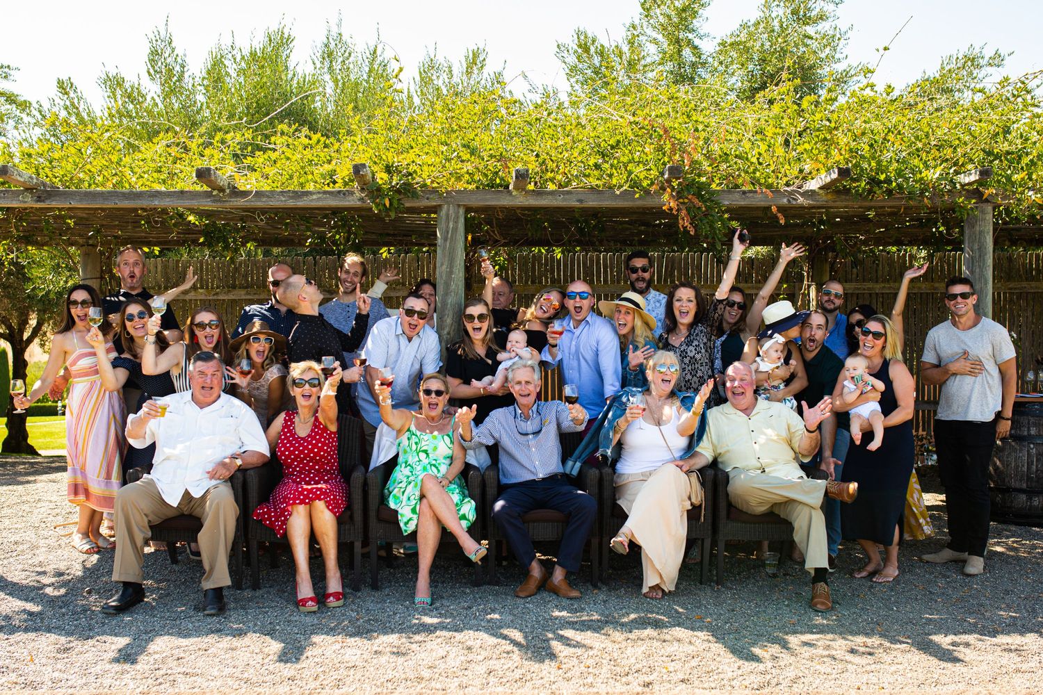 Large group photo of event attendees seated together under an outdoor pavilion.