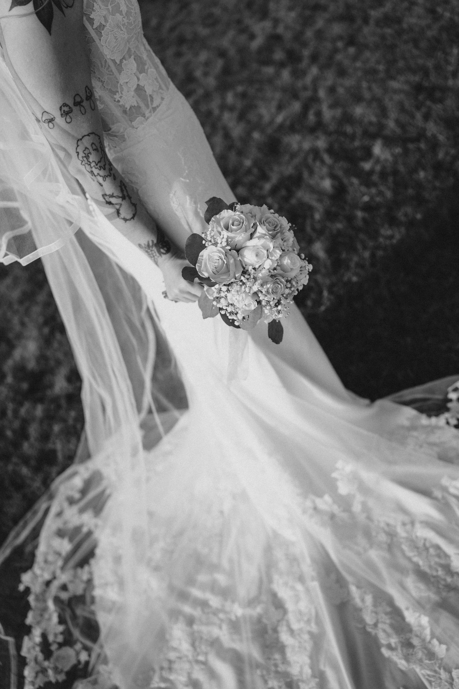 Close-up shot of white and red flowers being held against a white dress in natural sunlight.