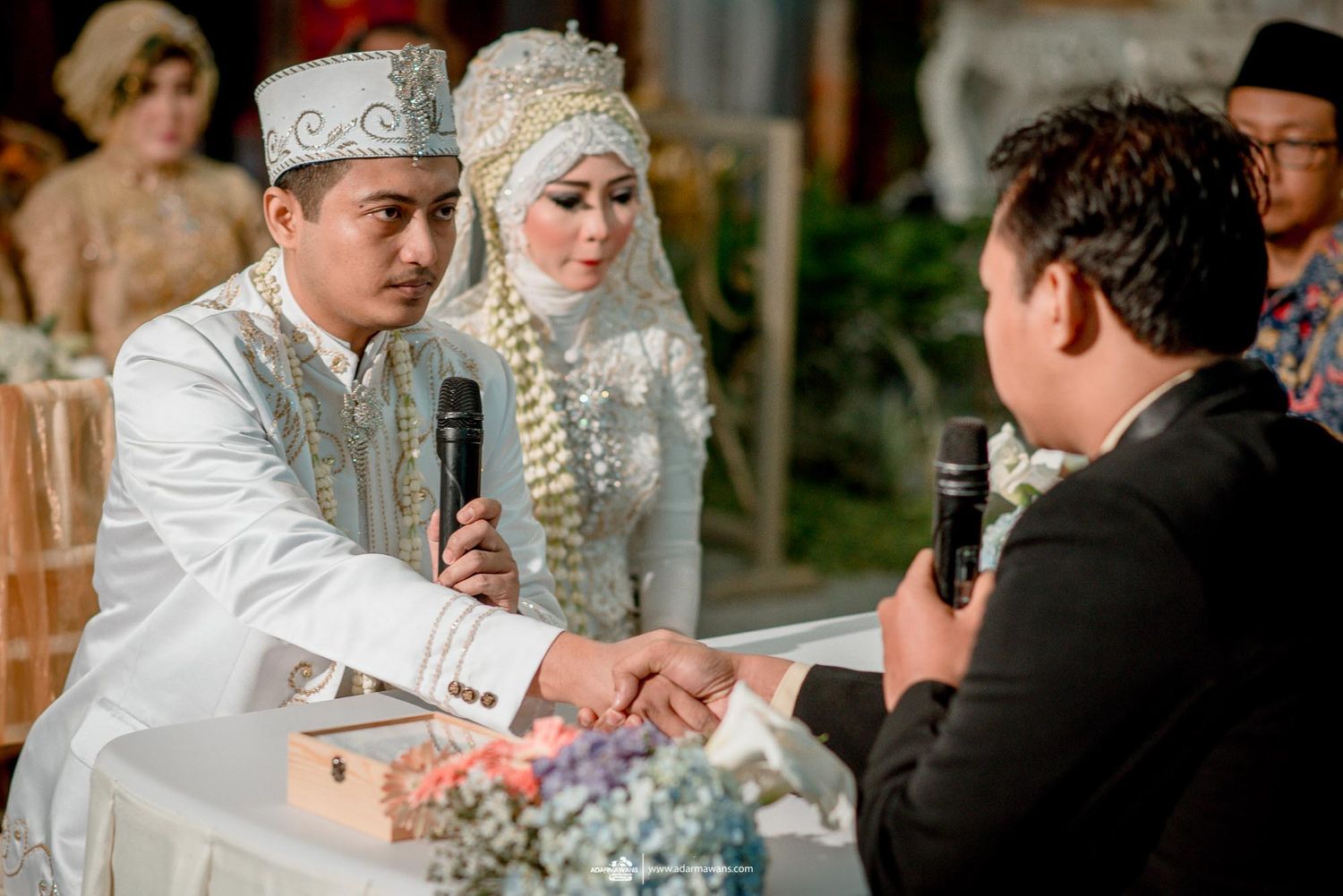 Traditional wedding ceremony with couple in white and silver attire.
