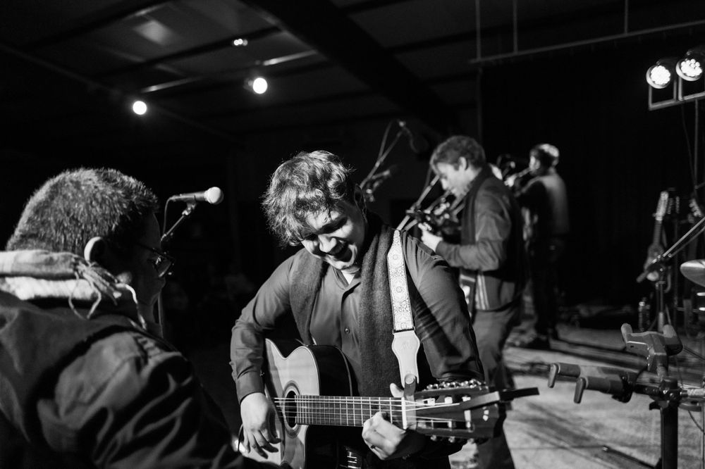 Musicians perform together on stage in an intimate black and white concert photo.