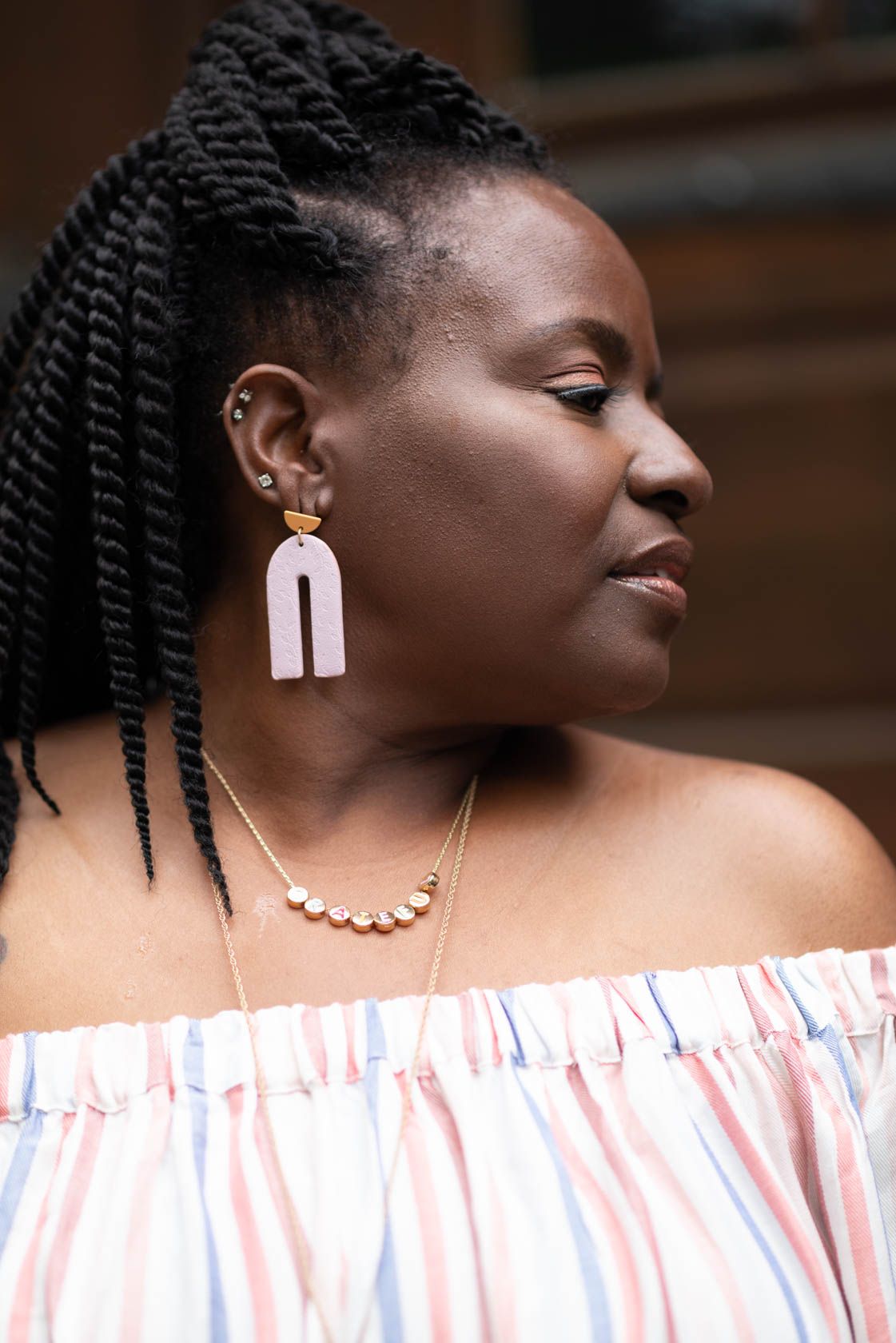 Pixs By Tina captured Leslie Crudup a public speaker wearing a white off-shoulder top and statement earrings with braided hair.