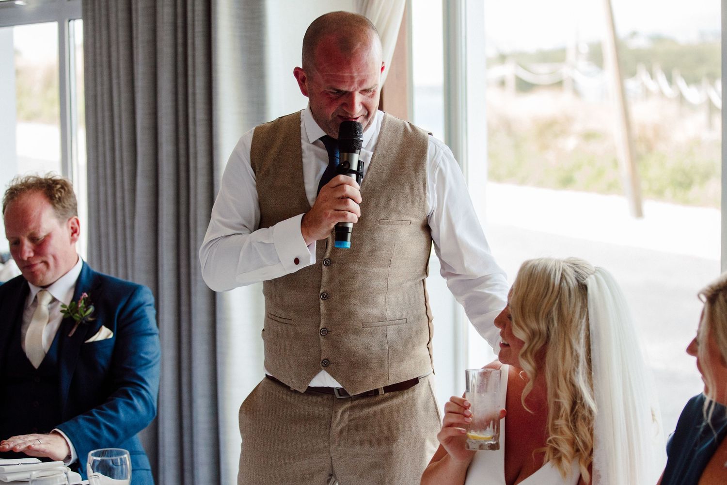 Wedding speaker gestures while giving an emotional toast at reception.