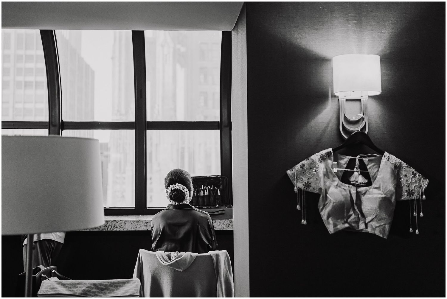Black and white artistic composition showing a window view and hanging garment with lamp.