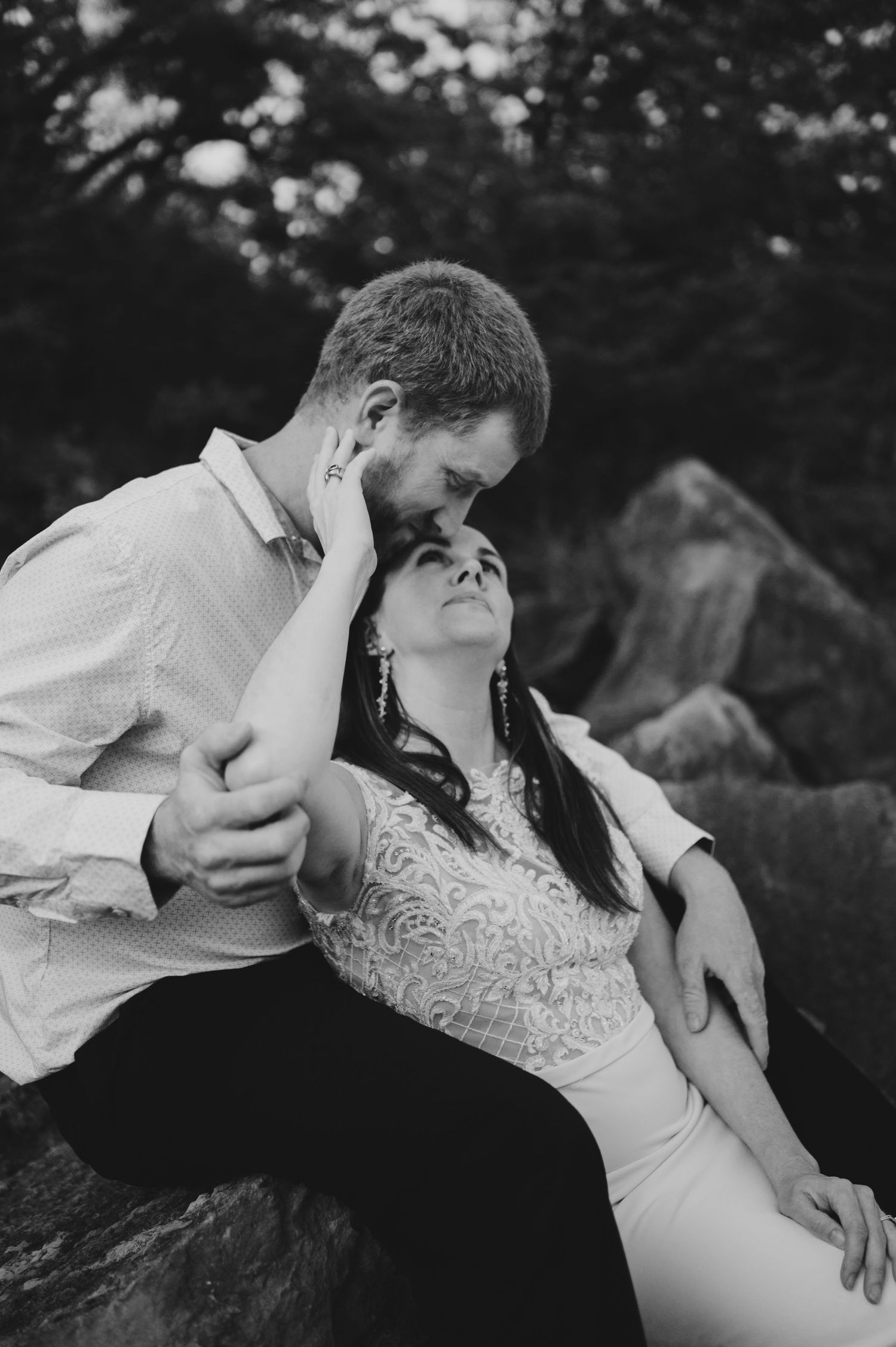 An intimate black and white romantic moment captured between a couple on natural rock formations.