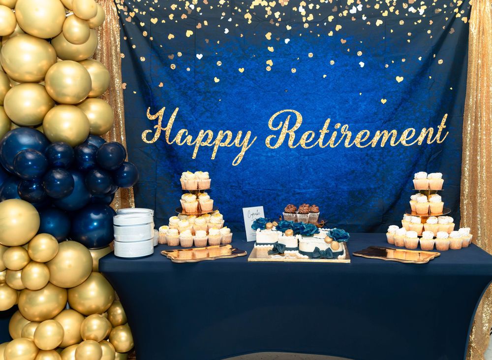 Elegant retirement party setup with gold and navy balloon decor against blue backdrop.