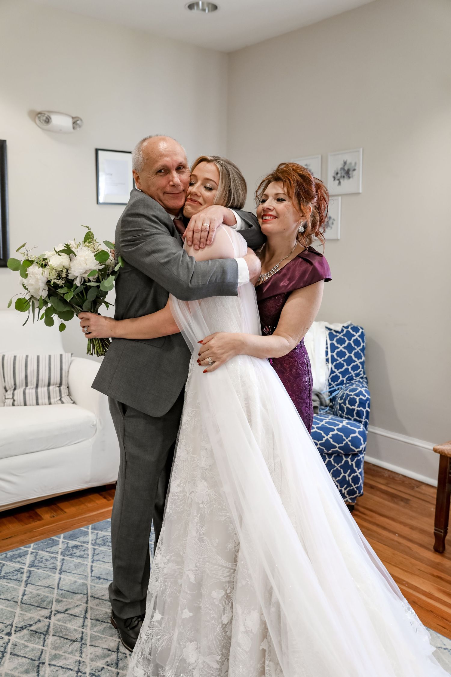 Emotional wedding day embrace in a bright living room with white decor.