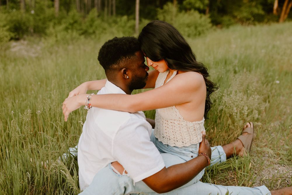 Intimate couple sharing tender moment together in summer meadow at golden hour.