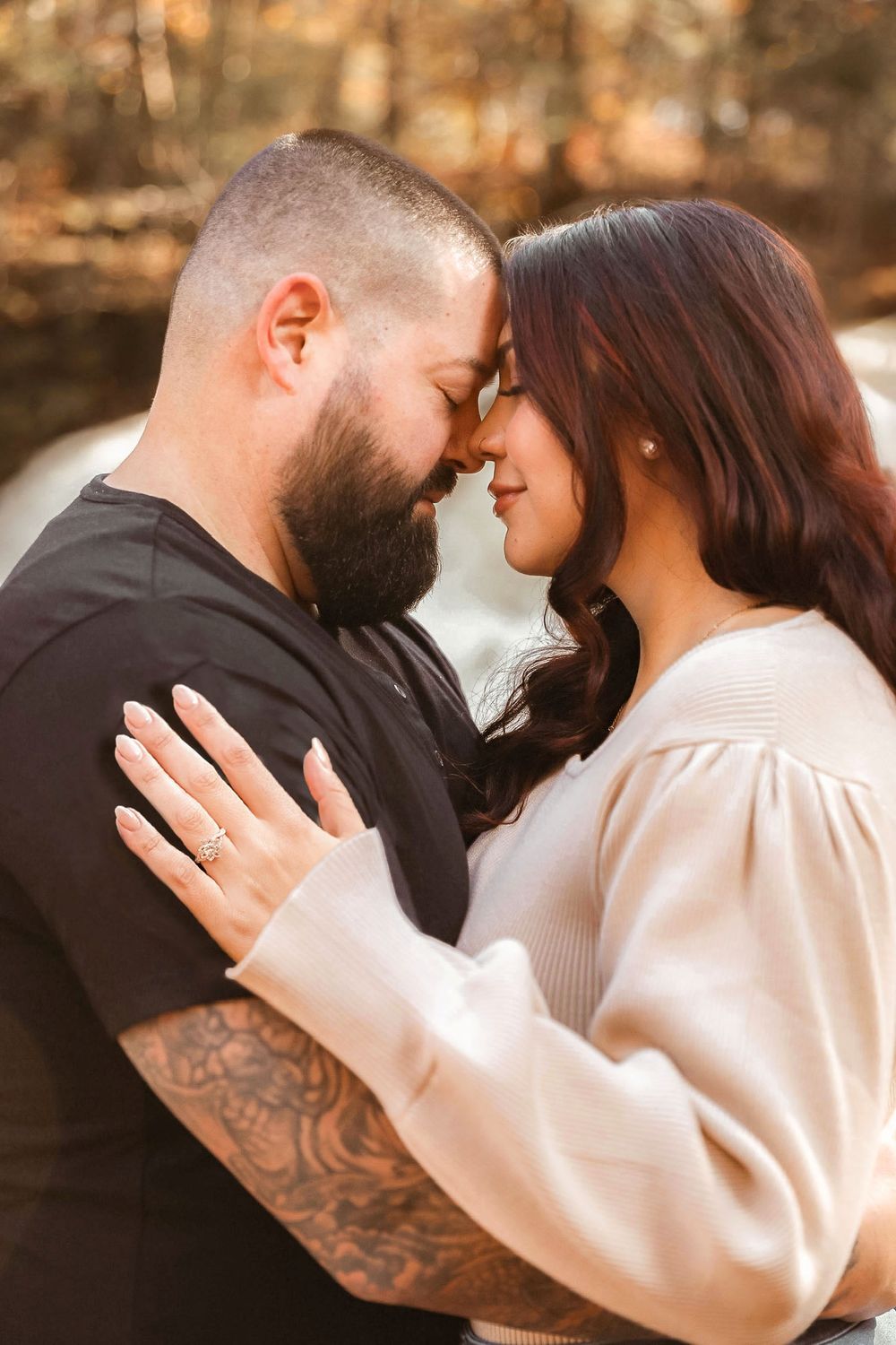 Romantic outdoor portrait of couple touching foreheads in autumn setting.