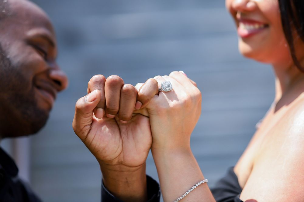 Close up shot of couple holding hands with engagement ring visible.