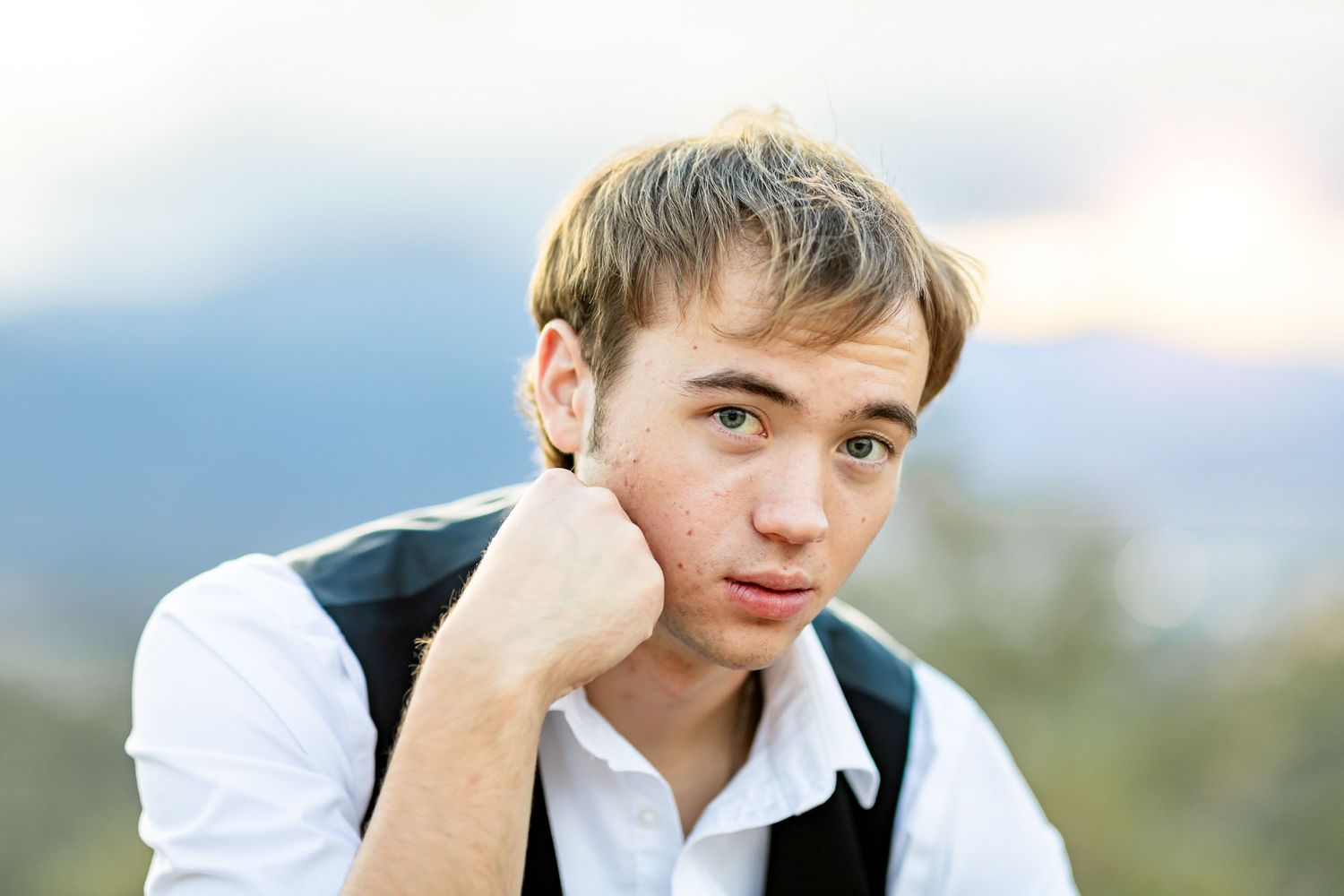 Senior guy leans on one hand and gazes solemnly at the camera at his senior session at Palmer Park in Colorado Springs.
