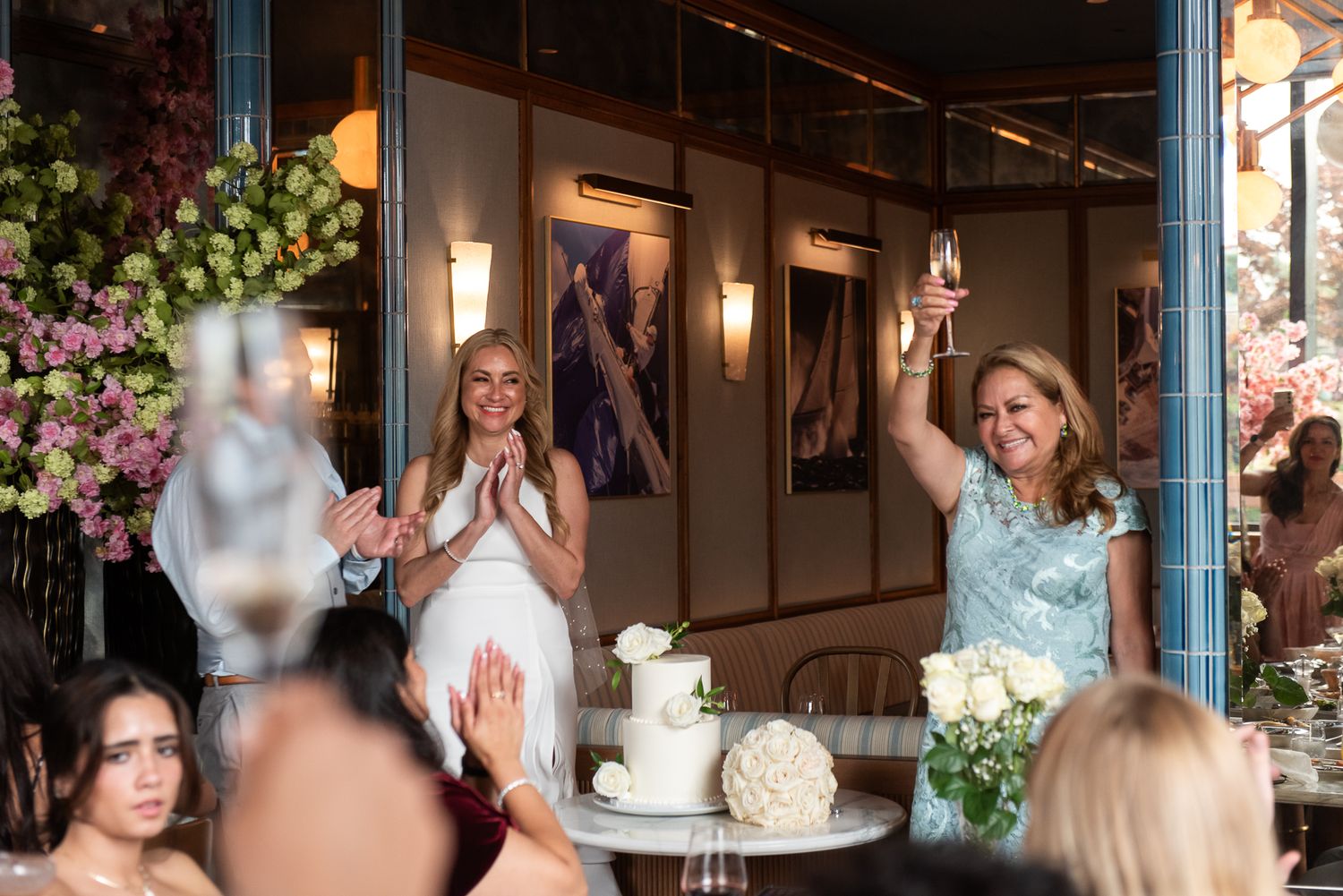 Elegant wedding celebration with floral decorations and a white tiered cake in an upscale venue.