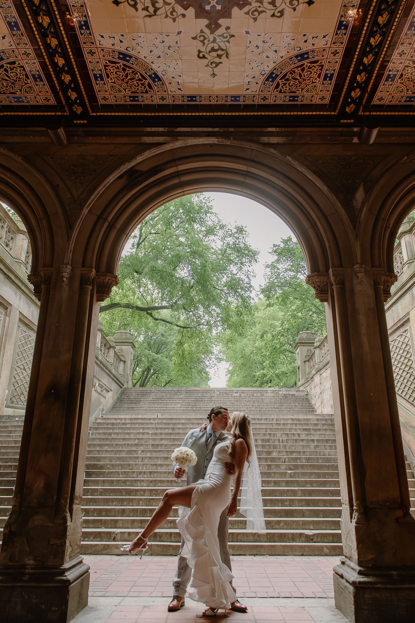 Romantic couple photos under ornate archway with stone steps in background.
