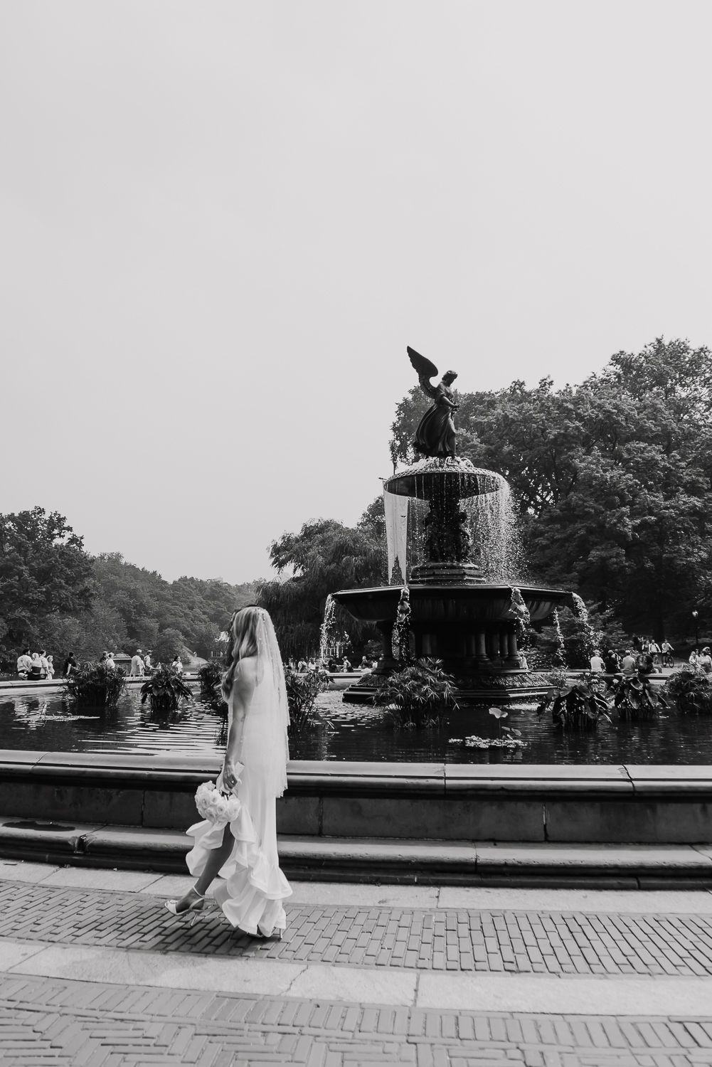 Black and white photos of a bride walking past the Bethesda Fountain in Central Park.