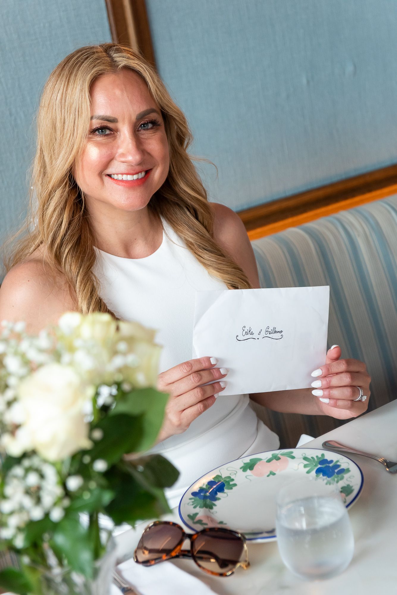 Wedding day details with letter and floral arrangements on blue sofa.