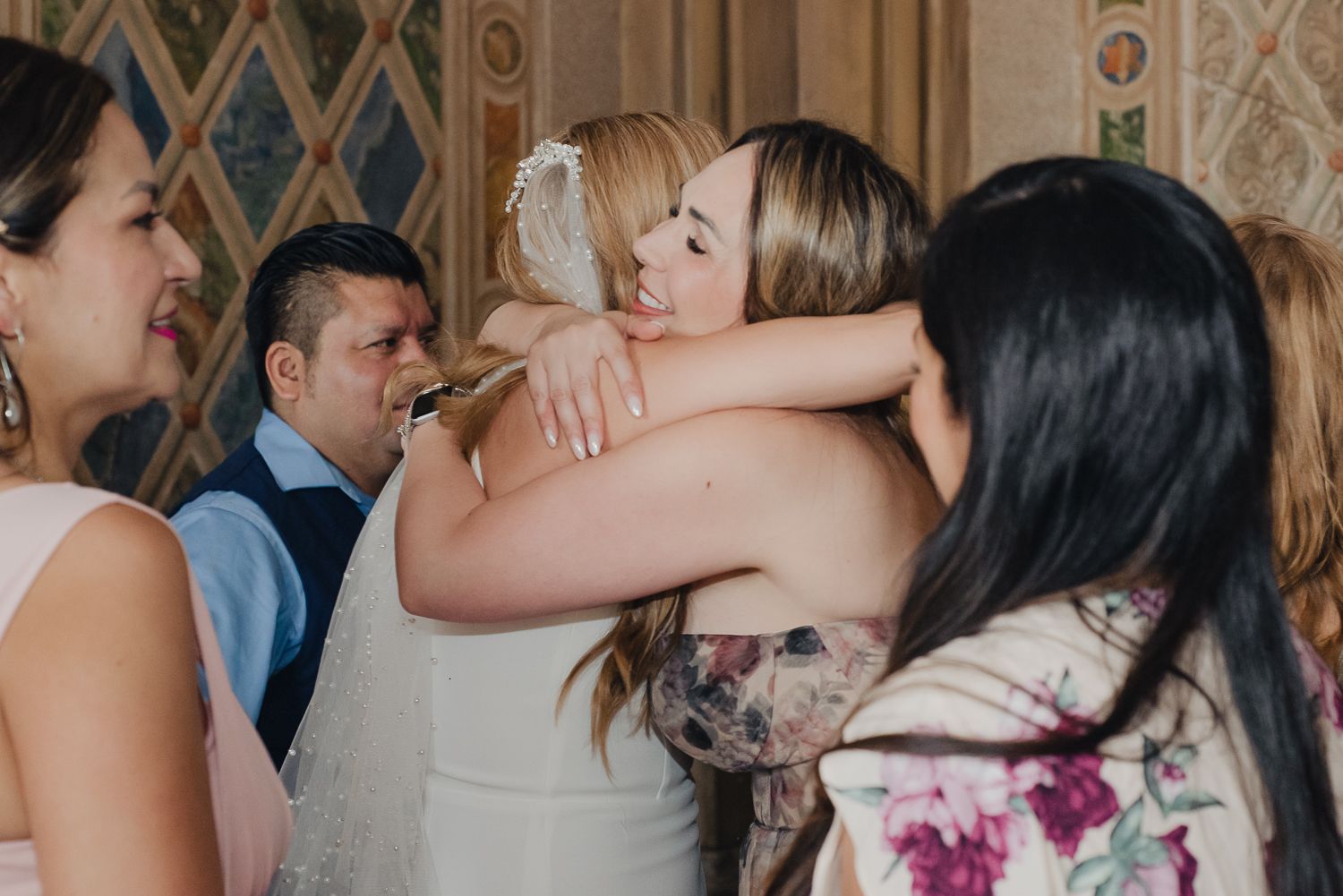 Wedding guests dancing and celebrating on the dance floor at an indoor reception venue.