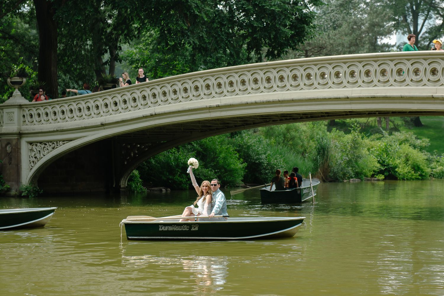 Wedding photography session with rowboats on Central Park lake near Bow Bridge.