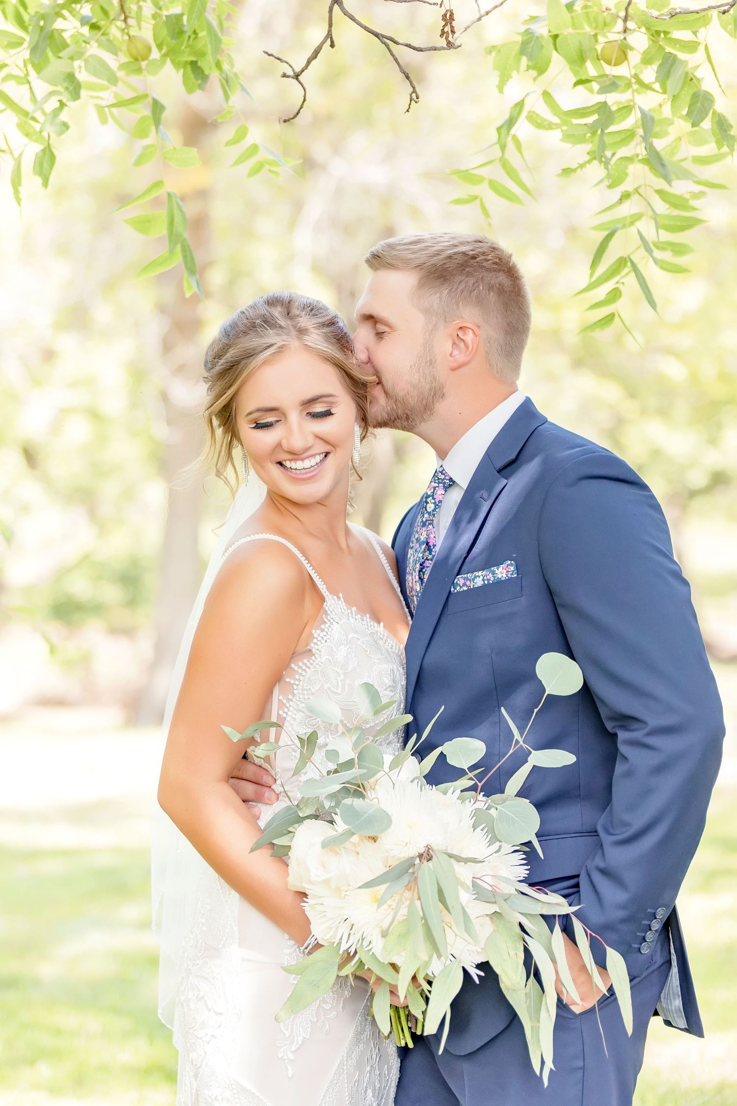A bride and groom share intimate moments in white and navy attire during their wedding at Winan Creek Event Center