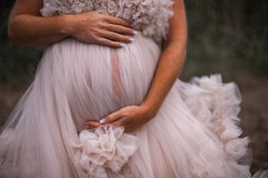 Detail shot of tulle maternity dress with hand resting on baby bump.