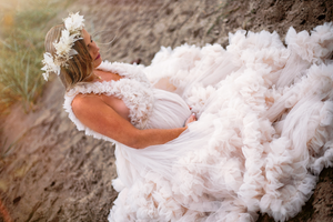Elegant white ruffled gown photographed in outdoor natural setting.