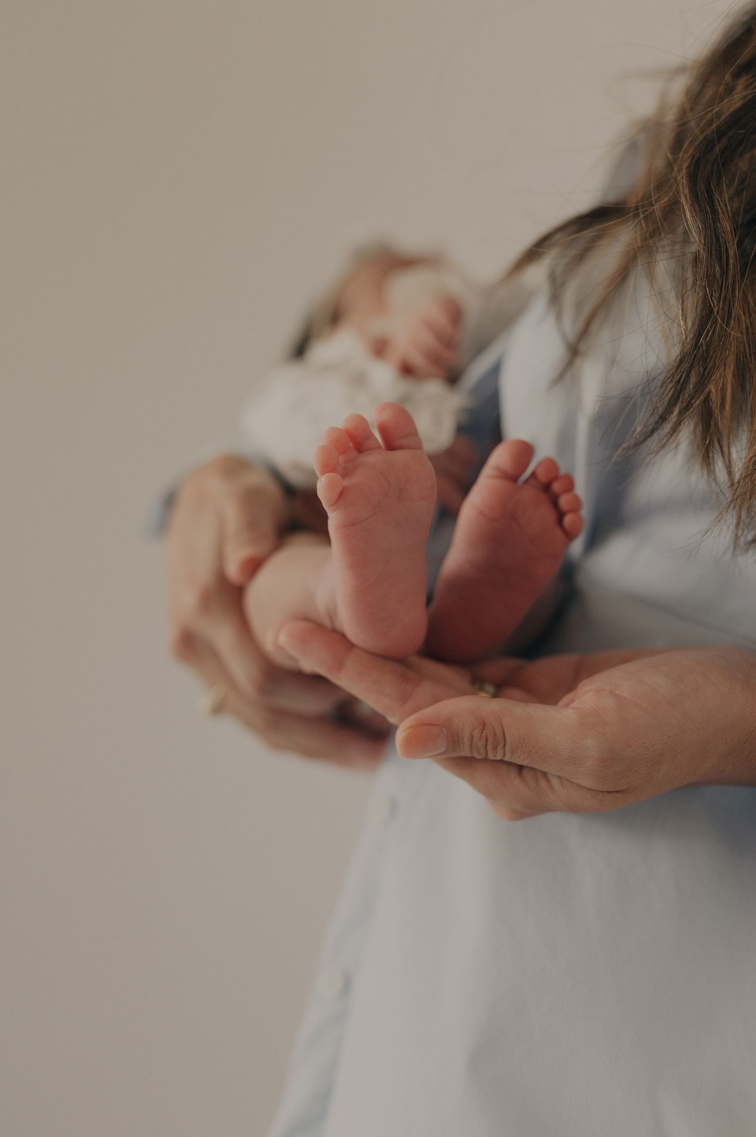 Close-up of tiny newborn baby feet cradled in gentle hands.