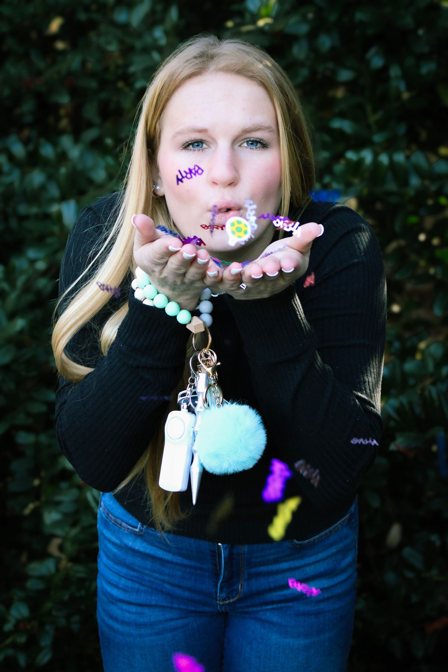 Colorful keychain charms and trinkets displayed in cupped hands against a dark background.