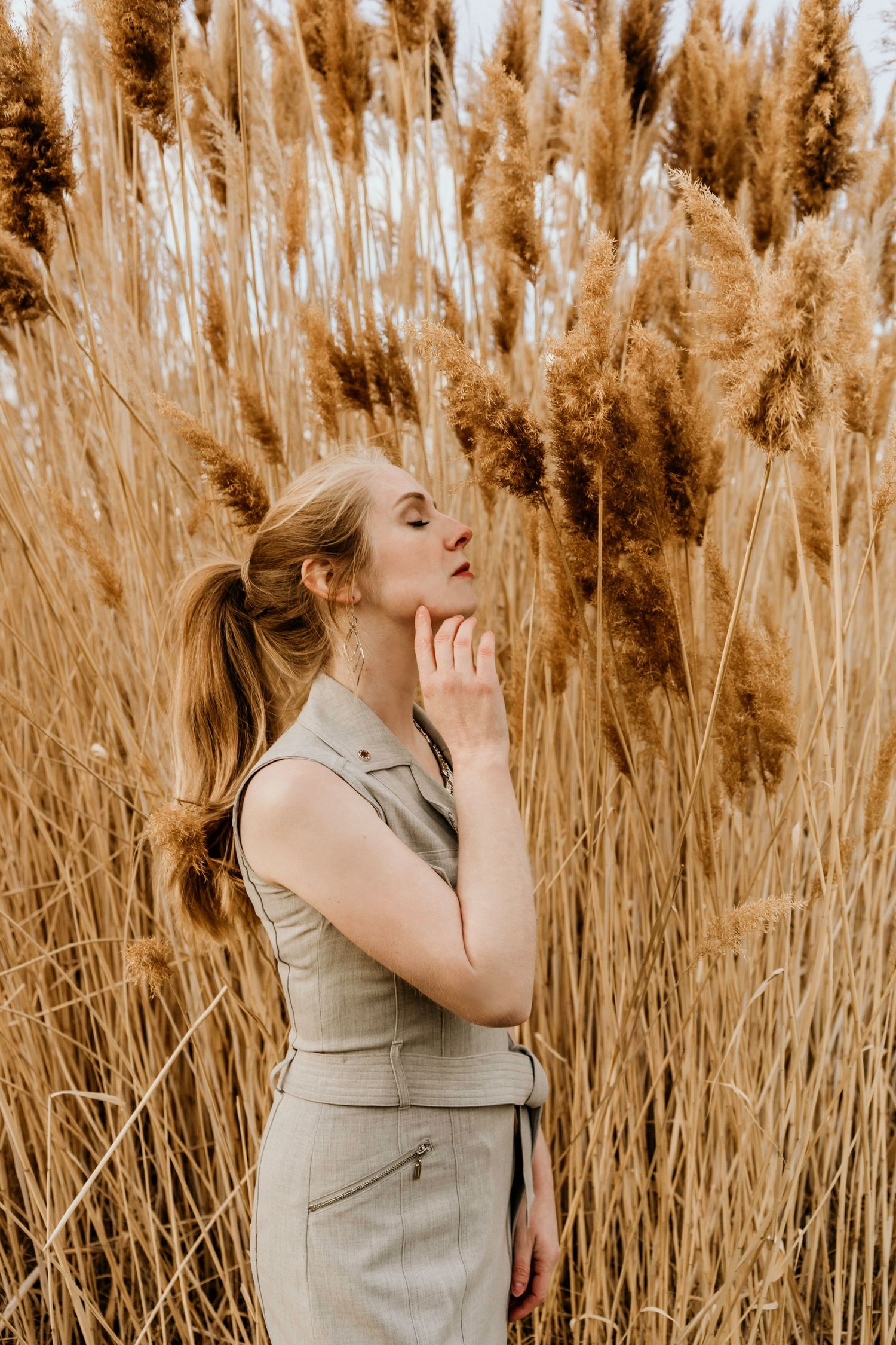 Portrait in warm sepia tones featuring beige dress against tall pampas grass background.