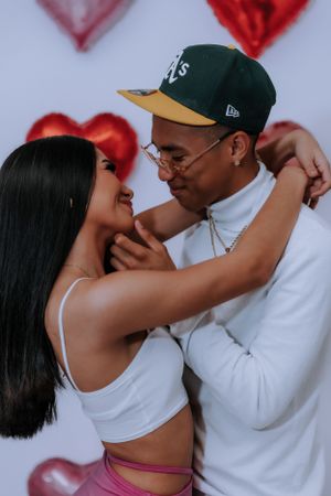 Romantic couple sharing intimate moment against heart balloon backdrop.