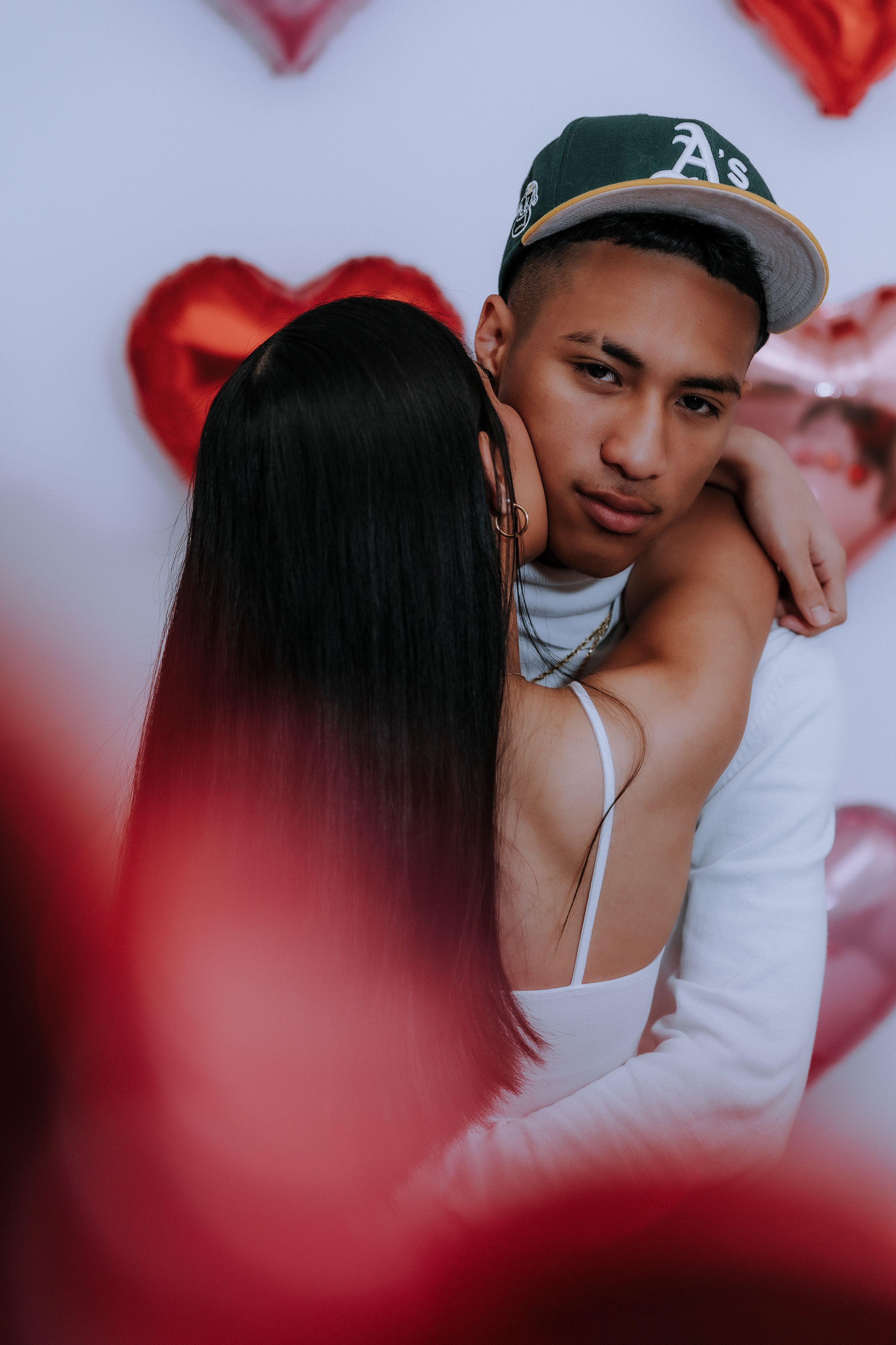 Close-up romantic portrait against backdrop of red heart balloons.