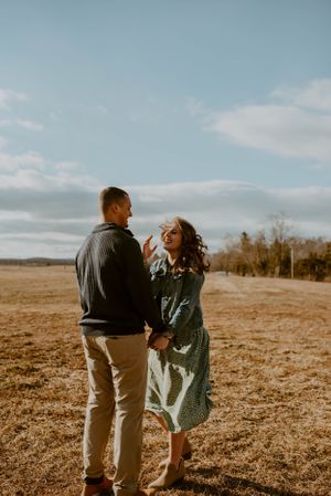 Couple sharing a tender moment in an open field during golden hour.